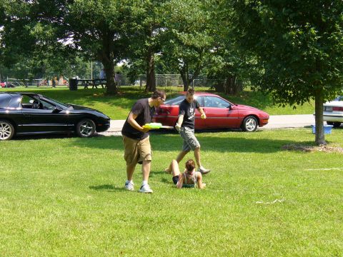 1991 Ford Probe - People enjoying a sunny day with water guns in a park, with cars parked in the background.
