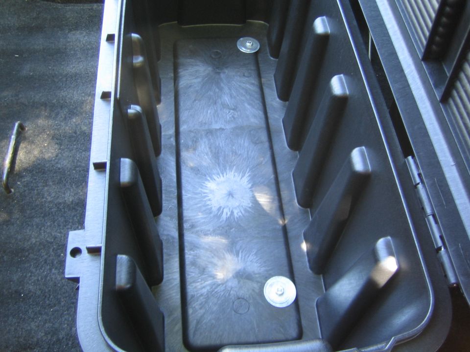 Interior of a black plastic storage box with ribbed sides and two visible mounting screws