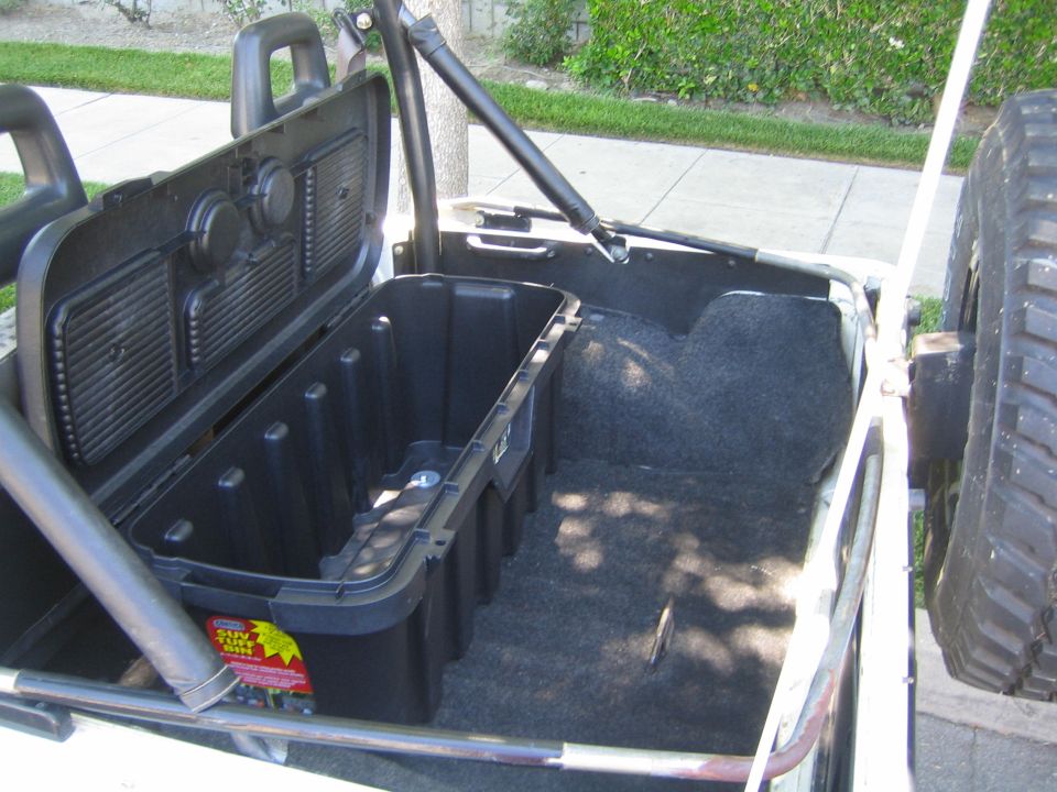 Rear cargo area of open-top 4x4 with black storage bin and folded seat