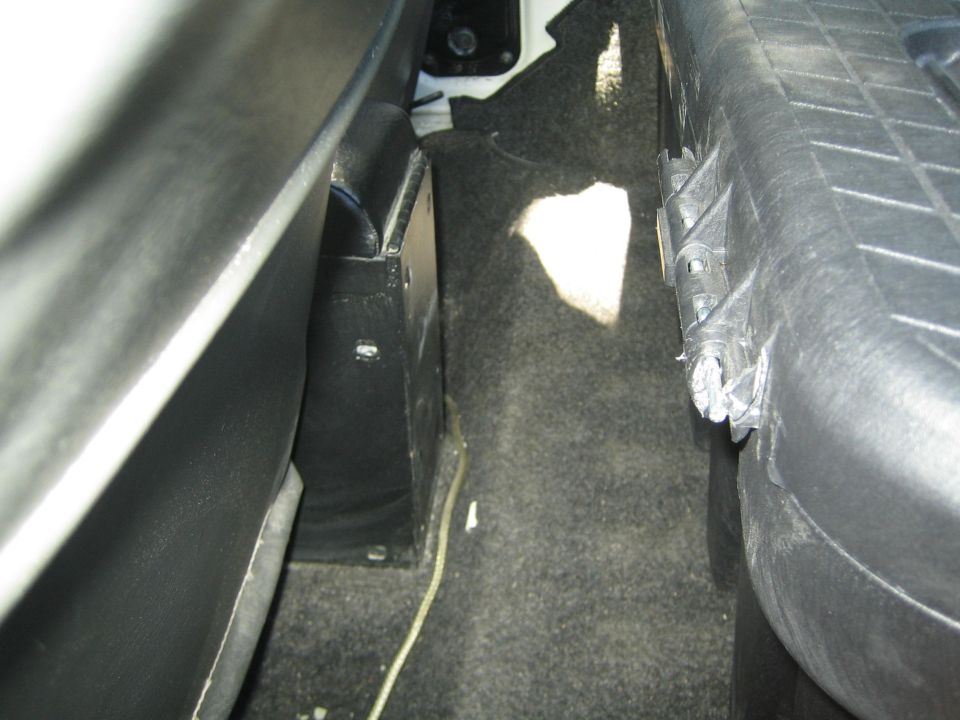 View of the cargo area floor between seats, showing carpet and a black plastic trim piece