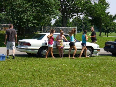 1991 Ford Probe - Several people gather around a white sedan on a sunny day.
