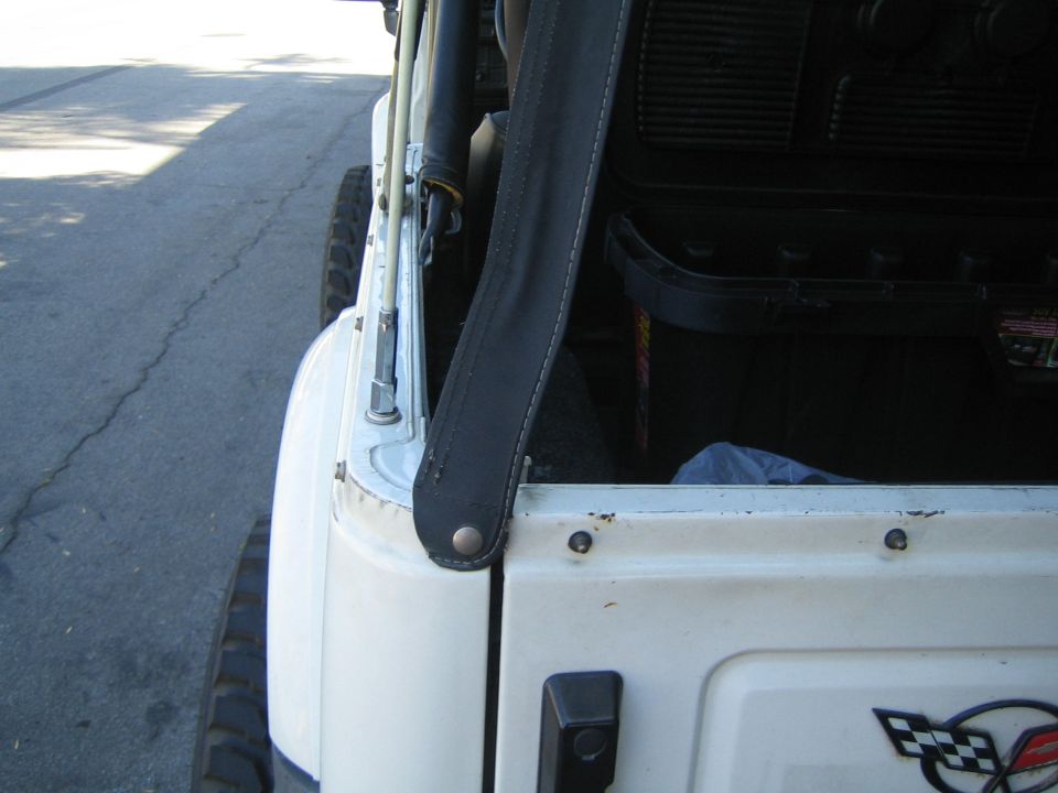 Side view of a white Jeep Wrangler's interior, showing the door frame, seatbelt, and part of the dashboard