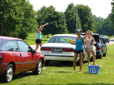 1991 Ford Probe - A red coupe and a white sedan are parked on a grassy area with trees in the background.