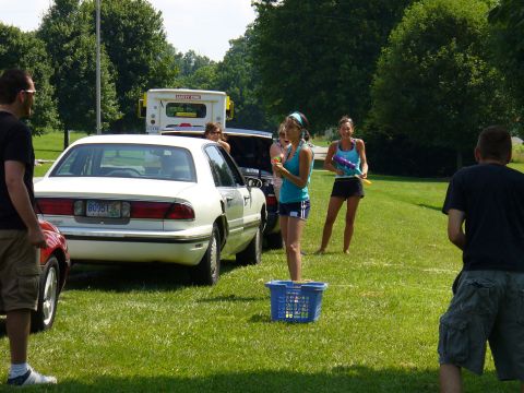 1991 Ford Probe - People gathered around a white sedan on a sunny day, some holding water guns.