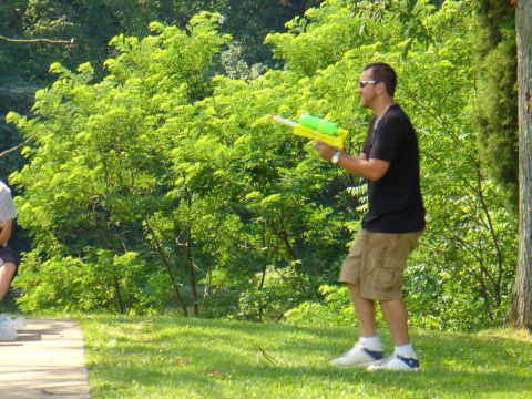 1991 Ford Probe - A man stands in a grassy area with trees in the background, holding a water gun.