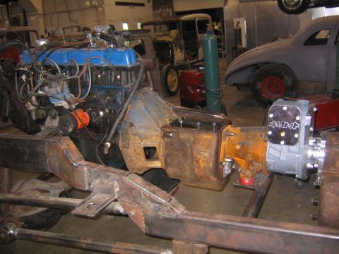 1982 Ford Bronco - A vehicle's engine and transmission are mounted on a custom frame in a workshop setting with other vehicles present.