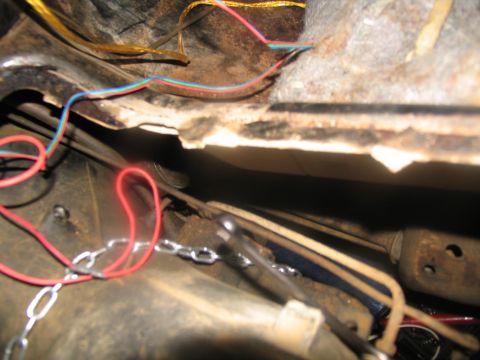 1978 Ford Bronco - Close-up view of wiring and a chain attached to the undercarriage of a vehicle.