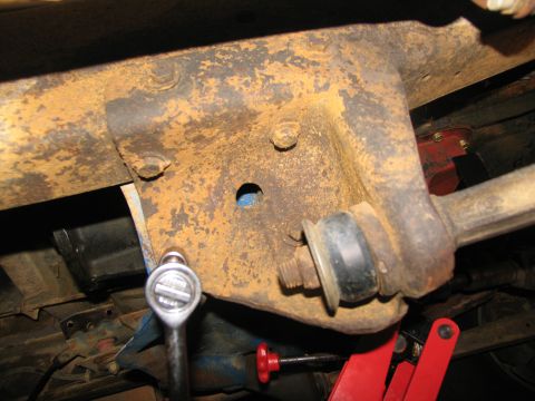 1978 Ford Bronco - Socket wrench engages a bolt on a corroded vehicle frame bracket, suggesting mechanical work.