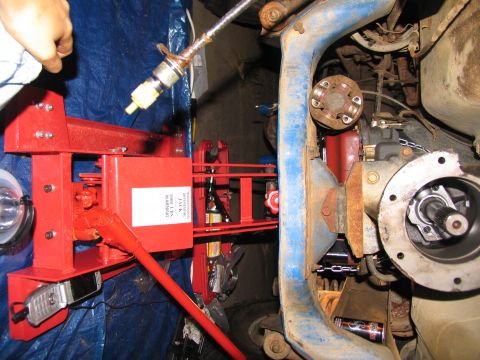 1978 Ford Bronco - A red jack is positioned near the vehicle's drivetrain, with a cell phone attached to the jack's base.