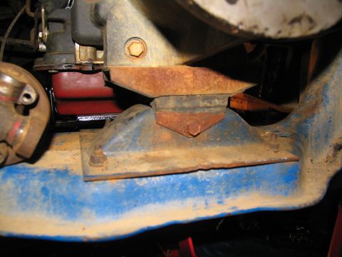 1978 Ford Bronco - Close-up view of a rusty engine mount assembly, a red transmission cushion.