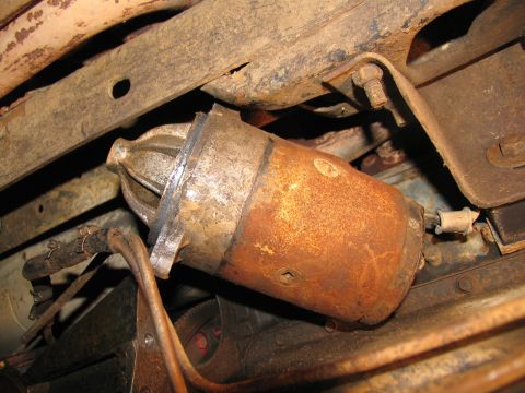 1978 Ford Bronco - Close-up view of a corroded starter motor, likely removed for transmission work.