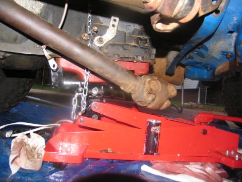 1978 Ford Bronco - Underneath view of a vehicle's driveshaft and transmission, supported by a jack during maintenance.