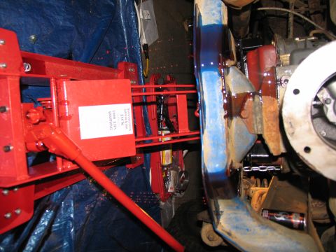 1978 Ford Bronco - Close-up view of a red jack mechanism and vehicle frame, with engine components and a can visible.