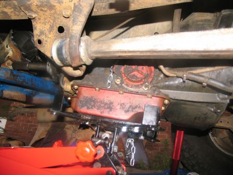 1978 Ford Bronco - Underside view of a vehicle's transmission being lowered with a jack and chains, indicating maintenance or repair work.
