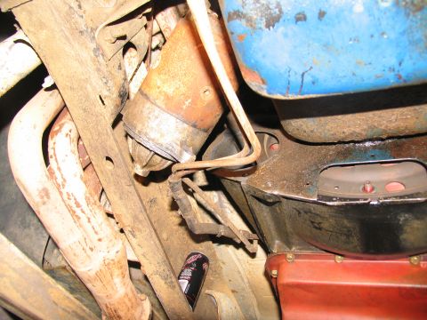 1978 Ford Bronco - Underside view of a vehicle's starter motor and exhaust manifold, with a can of spray paint visible.