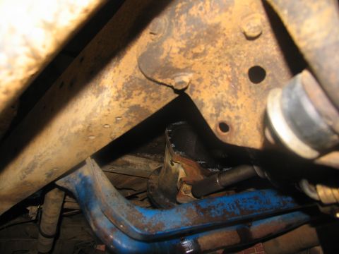 1978 Ford Bronco - Underside view of a vehicle's frame and suspension system, showing various metal components and rust.