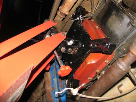1978 Ford Bronco - Orange transmission jack arms are positioned to support a black bracket with red accents during removal.