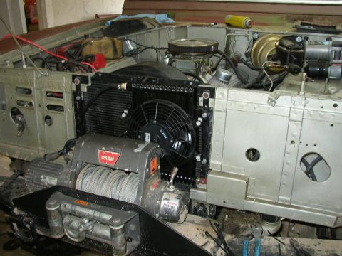 1995 Ford Bronco - The engine bay of a vehicle is partially disassembled, revealing the radiator, fan, and a WARN winch.