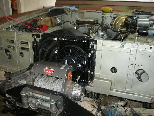 Engine bay of a vehicle with a WARN winch mounted on the front, showing the radiator and fan
