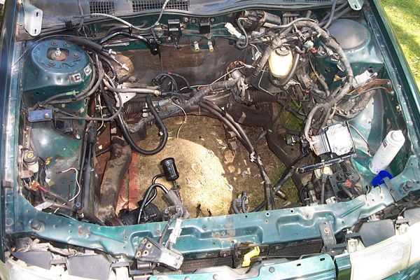 Green 1995 Ford Taurus engine bay with engine removed, showing wiring and components