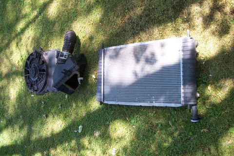 1995 Ford Taurus - Radiator and air intake assembly removed from a vehicle and placed on the grass.