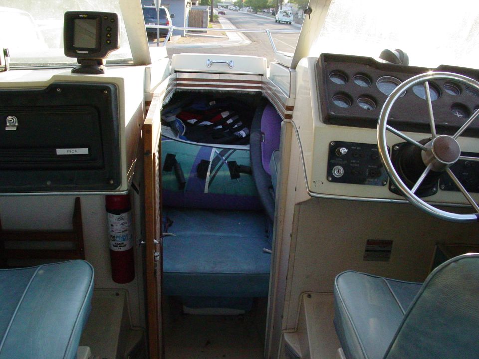 Boat cockpit interior with steering wheel, gauges, blue vinyl seats and cuddy cabin cushions