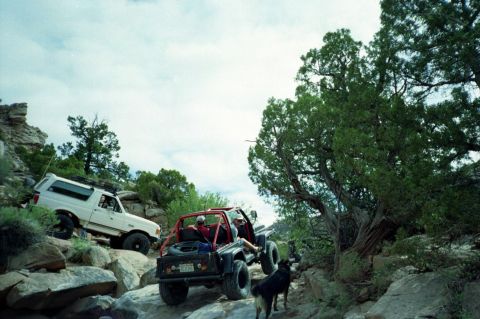 1982 Ford Customline - Two off-road vehicles navigate a challenging rocky trail under a cloudy sky.