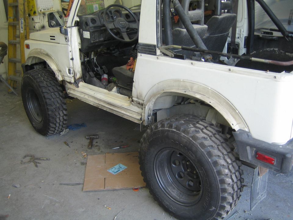 White Suzuki Samurai with doors removed, showing interior and large off-road tires