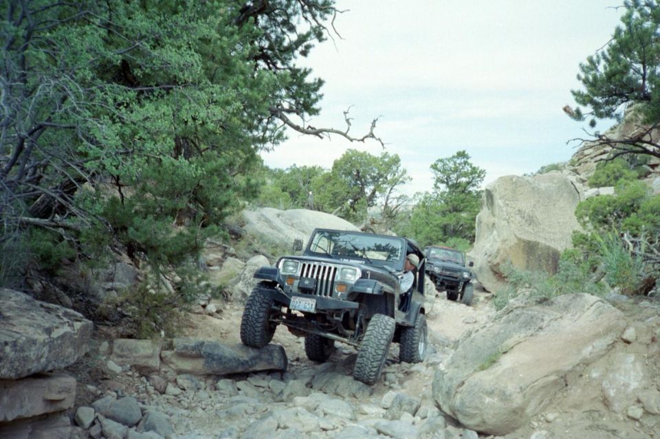 Gray topless Jeep Wrangler YJ crawling over rocks on a desert trail