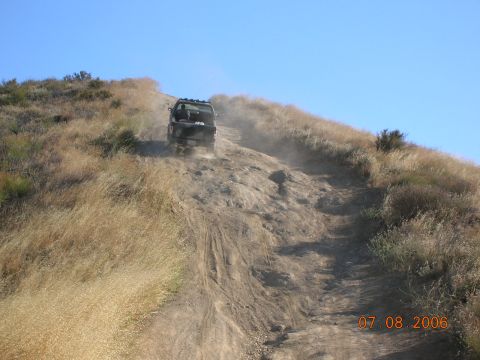 1985 Ford Bronco - A vehicle navigates a challenging off-road trail on a sunny day.
