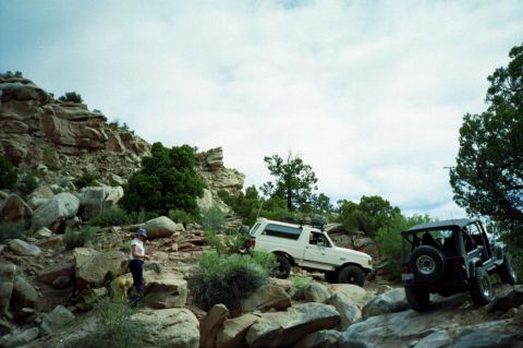 1982 Ford Customline - Two off-road vehicles navigate a challenging rocky trail under a cloudy sky.
