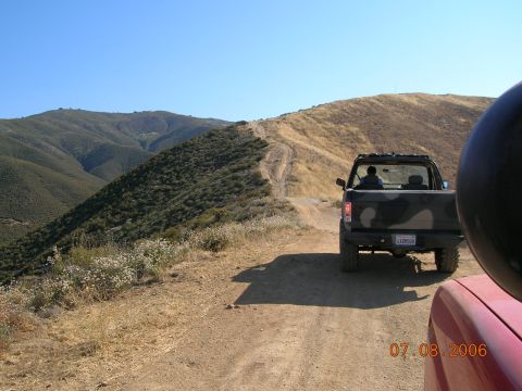 1985 Ford Bronco - Off-roading in a 1985 Ford Bronco on a dusty mountain trail with a second vehicle following.