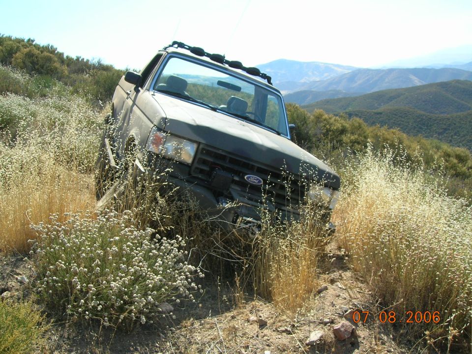 Dark green 1985 Ford Bronco on a hillside with dry grass
