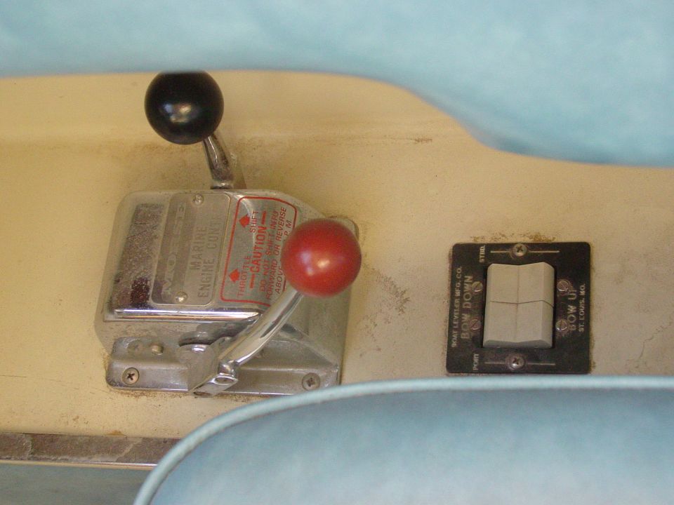 Marine engine control levers and BOW UP/DOWN trim rocker switch on a cream boat dash