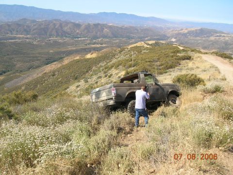 1985 Ford Bronco - A person stands next to a Ford Bronco on a grassy, mountainous terrain.