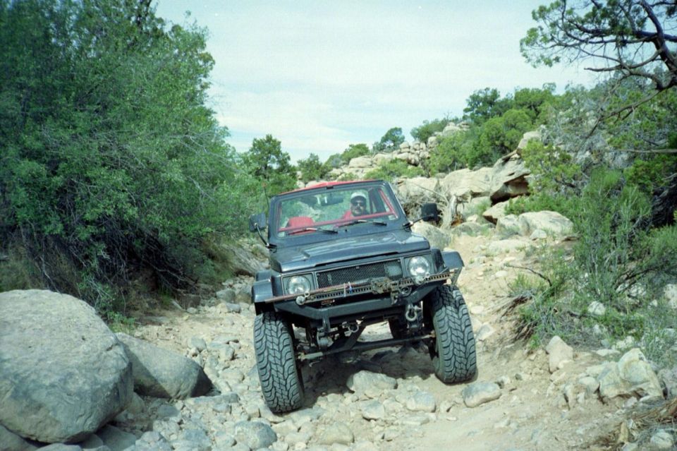 Black open-top 4x4 crawling over rocks on a desert trail
