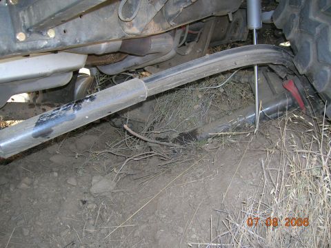 1985 Ford Bronco - Bent suspension component and exhaust pipe visible on a vehicle's undercarriage.