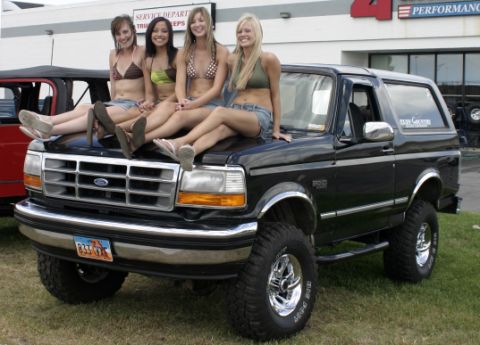 1986 Ford Bronco - A black Ford Bronco from the early 1990s is shown with four women posing on its hood.