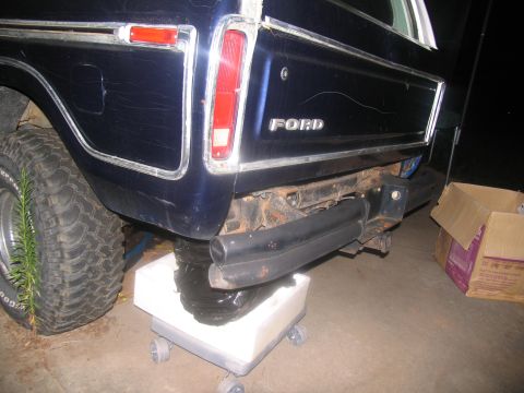 1978 Ford Bronco - Fluid drains from the rear of a 1978 Ford Bronco into a catch pan during transmission removal.
