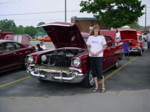 1972 Ford Ranchero - A woman poses with a classic 1957 Chevrolet Bel Air at an outdoor car show.
