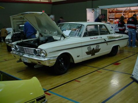 1972 Ford Ranchero - A white 1962 Ford Falcon Thunderbolt is displayed with its hood open, racing graphics and black wheels.