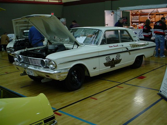 White 1962 Ford Falcon Thunderbolt with hood open, black wheels, and racing decals