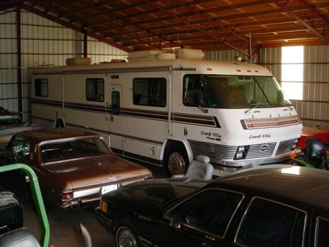 1972 Ford Ranchero - A white motorhome with brown stripes is parked inside a garage, alongside other vehicles.