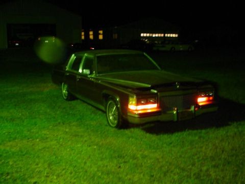 1972 Ford Ranchero - A maroon sedan sits on a grassy lawn at night, its headlights and taillights illuminated.