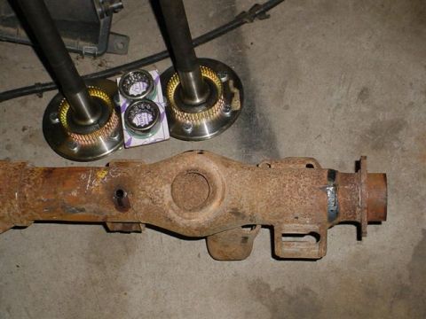 1972 Ford Ranchero - A rusty rear axle assembly is shown with two axle shafts and new bearings, likely for a vehicle repair or restoration project.