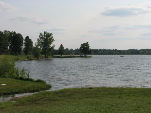 2003 Ford Crown Victoria - A wide view of a lake on a cloudy day, with trees lining the distant shore and a small boat visible on the water.