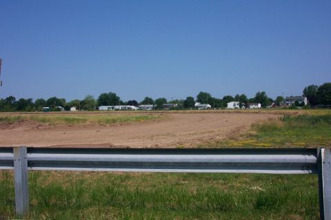 1978 Ford Bronco - A wide view of a dirt field and surrounding residential area under a clear blue sky.