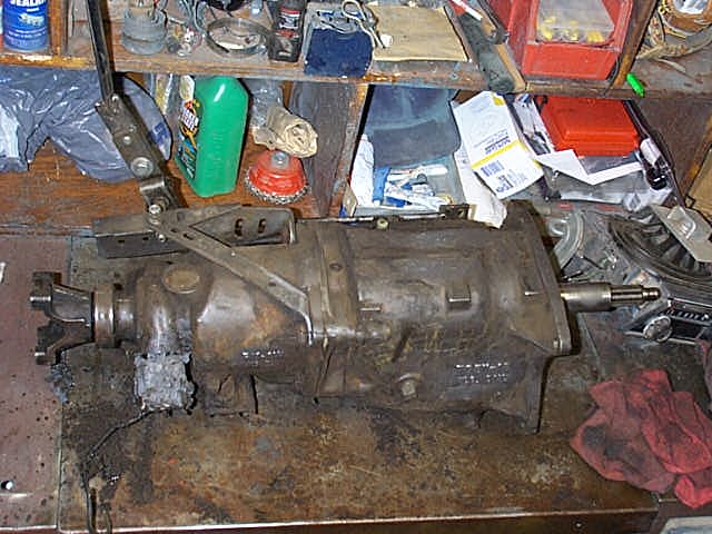 Removed manual transmission on a cluttered workbench, tailshaft facing right