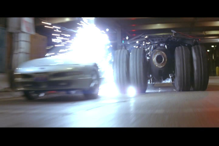 Film still of an armored vehicle chasing a car amid bright sparks