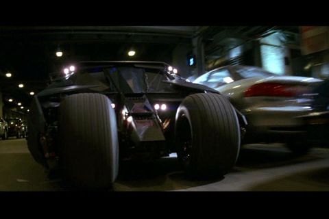 1994 Ford Probe - A custom armored vehicle with massive rear tires is shown in a dark setting, with another car blurred in the background.
